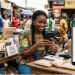 Young Ivorian entrepreneur using smartphone to manage WhatsApp Business